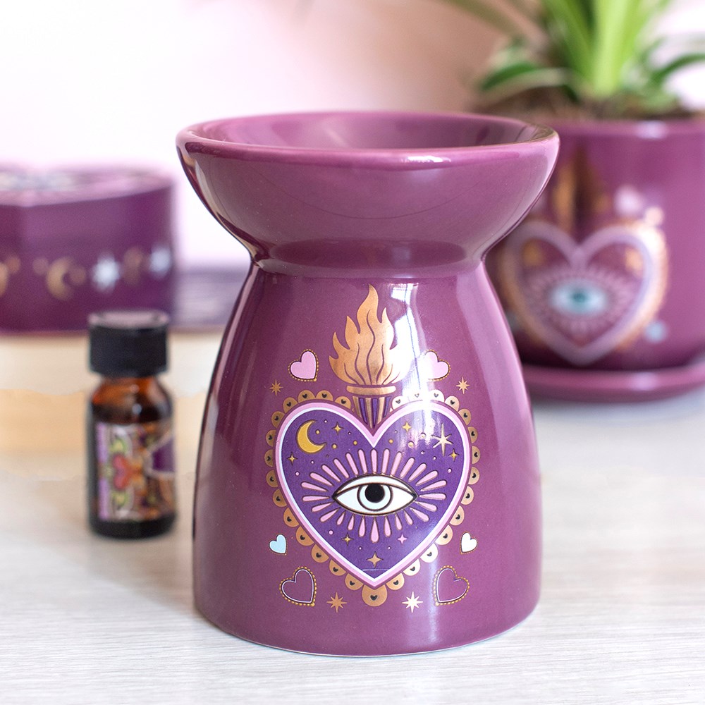 Brûle-parfum mauve décoré d’un cœur avec un œil, une flamme dorée et des motifs célestes